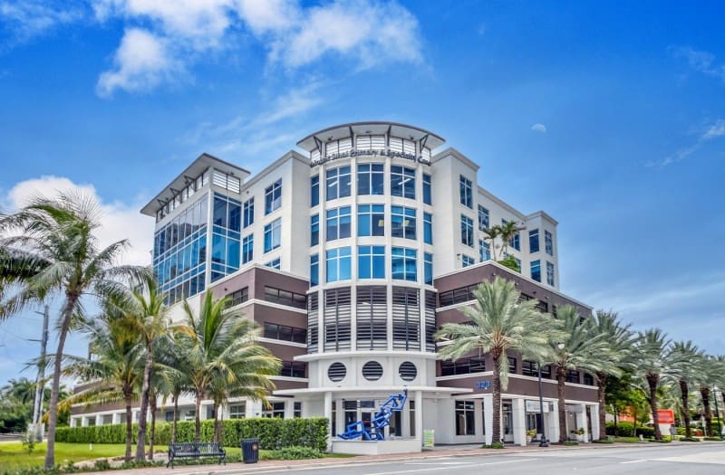 S3M Security office building exterior located in a modern business plaza with palm trees and glass facade architecture